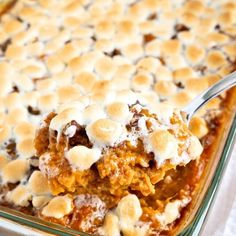 a casserole dish with marshmallows on top and a spoon in it