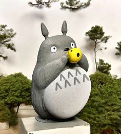 a statue of a bird with a yellow ball in its mouth and another animal on it's back