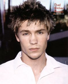 a close up of a person wearing a white shirt and hair in the middle of his face