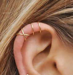 an ear piercing with three thin gold barbells on it's side, and the words handmade at amazon written below