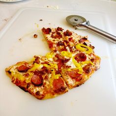 two slices of pizza sitting on top of a cutting board next to a spatula