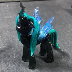 a glass figurine of a blue and black pony with wings on its back