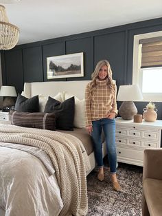 a woman standing next to a bed in a bedroom