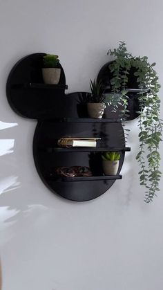 two black shelves with plants and books on them in the shape of mickey mouse heads