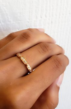 a woman's hand wearing a gold ring with three diamonds on the middle and side