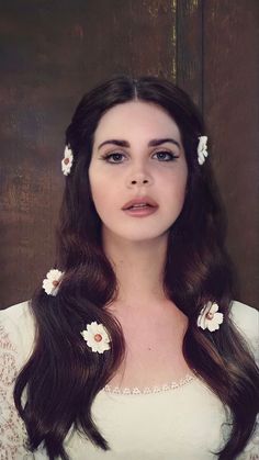 a woman with long brown hair and flowers in her hair, wearing a white dress