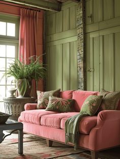 a living room with green walls and pink couch in front of a large potted plant