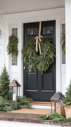 a black front door decorated with evergreen wreaths and pine cones for the holiday season