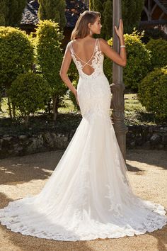 a woman in a wedding dress standing next to a lamp post with her back turned towards the camera