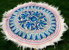 a blue and white round rug sitting on top of green grass