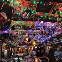 people are standing around in a bar decorated with christmas lights and decorations on the ceiling