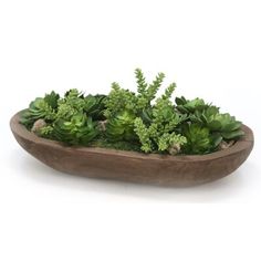 a wooden bowl filled with lots of green plants