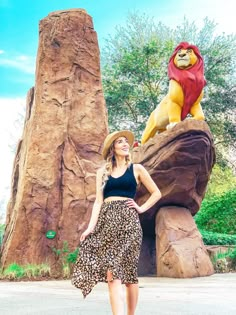 a woman standing in front of the lion king statue at disney's animal kingdom