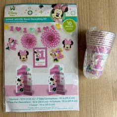 minnie mouse decorations and cupcake toppers on a wooden table with plastic wrapper