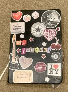 a notebook covered in lots of stickers and magnets on top of a carpet