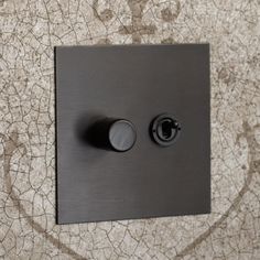 a black light switch sitting on top of a tiled wall next to a tile floor