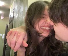 two young women are smiling and touching each other's foreheads in the bathroom