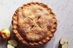 an apple pie and sliced apples on a marble counter top, with one slice taken out