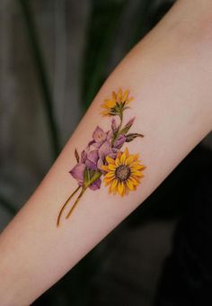 a woman's arm with flowers on it and one flower in the foreground