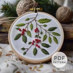 an embroidery pattern with red berries and green leaves on white fabric next to twine of twine