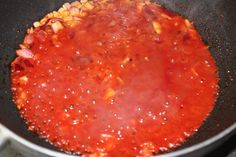 a pan filled with red sauce on top of a stove next to a frying pan