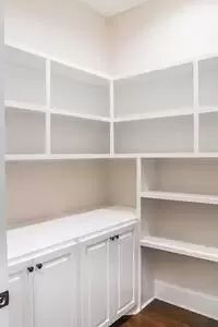 an empty room with white shelving and wood floors