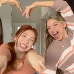 three girls are making a heart shape with their hands