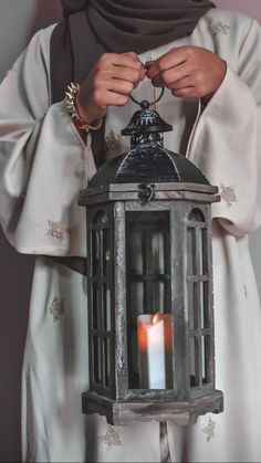 a woman holding a lantern with two candles in it