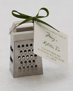 a small metal grater with a green ribbon tied around it's neck and tag