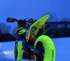 a yellow and black dirt bike sitting in the snow on top of it's wheels