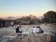 people sitting on benches in front of the acrobatic ruins