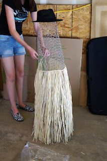 a woman standing next to a large piece of art made out of straw and plastic