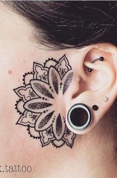 a close up of a person's ear with a tattoo design on the side