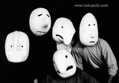 four people wearing masks with faces drawn on them