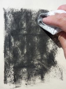 a hand holding a cloth over a black and white painting