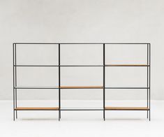 a black metal shelf with wooden shelves on each side against a white wall in an empty room