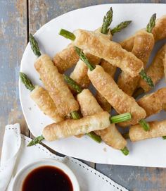 a plate with asparagus wrapped in bread on top of it next to a cup of coffee