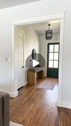 a living room with hard wood flooring and white walls, an open door leading into the dining area