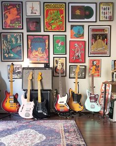 several guitars are lined up in front of a wall with posters on it and an area rug