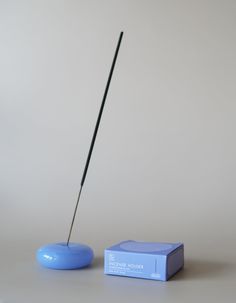 a blue object with a long stick sticking out of it's end next to a box