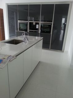 an empty kitchen with stainless steel appliances and white counter tops, along with newspaper on the floor