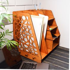 a laptop computer sitting on top of a desk next to a wooden book holder with holes in it