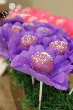 purple and pink cake pops with sprinkles on them sitting in a flower pot