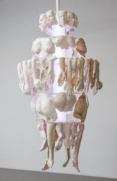 a sculpture made out of different types of human bodies hanging from a ceiling light fixture