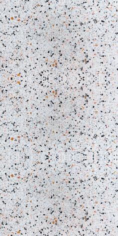 a white surface with black, orange and grey speckles on it's edges