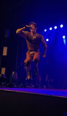 a man standing on top of a stage with his hands in the air while singing into a microphone