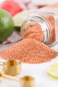 a jar filled with red sand next to limes and other ingredients on a table