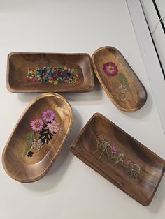 four wooden trays with beaded designs on them sitting on a white counter top