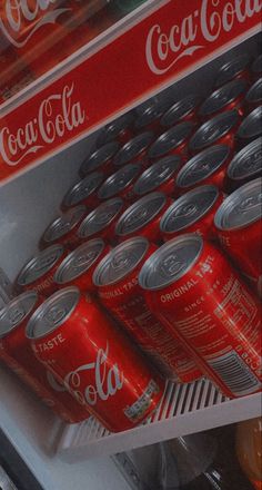 several cans of coca - cola are stacked on top of each other in a refrigerator