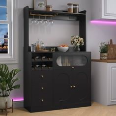 a black cabinet with wine glasses on top in a kitchen next to a potted plant